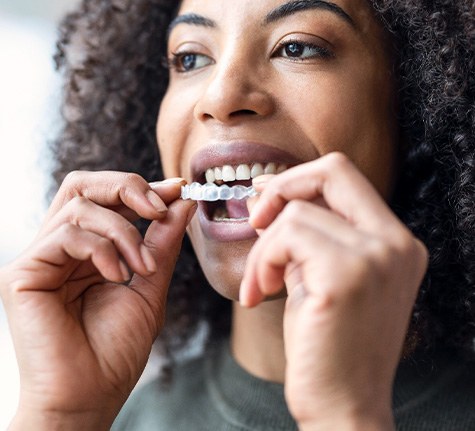woman putting Invisalign aligners in her mouth