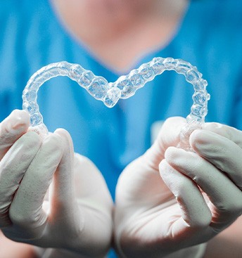 dentist making a heart shape with Invisalign trays