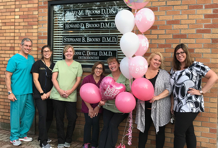 Team members posing together outside of dental office building