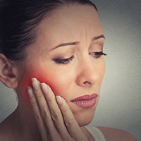 Woman holding cheek in pain