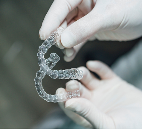 Dentist holding two Invisalign clear aligners