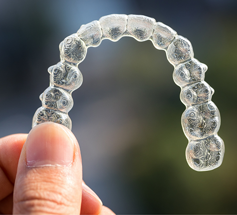 Hand holding an Invisalign aligner