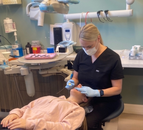 Smiling woman holding an Invisalign clear aligner