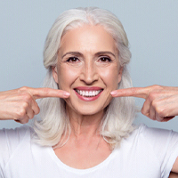 A woman pointing to her teeth after getting a smile makeover