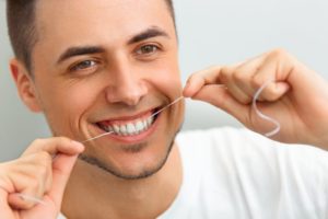 man smiling flossing his teeth