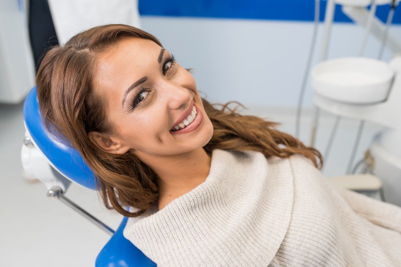 a young woman with straight teeth sitting in the dentist’s chair waiting for her appointment to begin