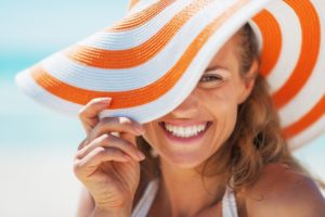 woman wearing a sunhat and following summer oral health tips