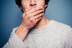 man covering her mouth because of the risks of store-bought teeth whitening