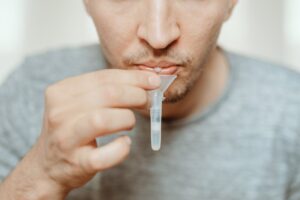 man spitting into an at-home saliva test tube