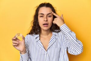 confused woman holding an Invisalign clear aligner